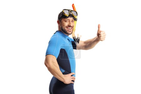 Photo for Young man in a diving suit putting on mask and gesturing thumbs up isolated on white background - Royalty Free Image
