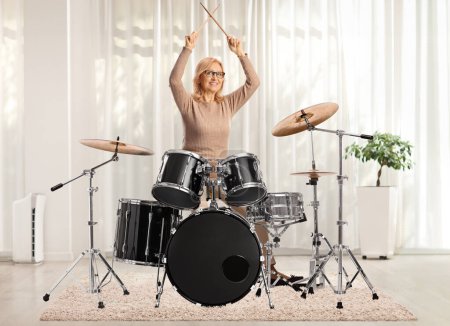 Photo for Middle aged woman playing the drums in a room - Royalty Free Image