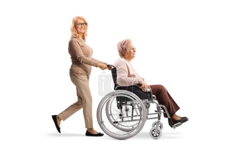Foto de Mujer empujando a su madre en una silla de ruedas aislada sobre fondo blanco - Imagen libre de derechos