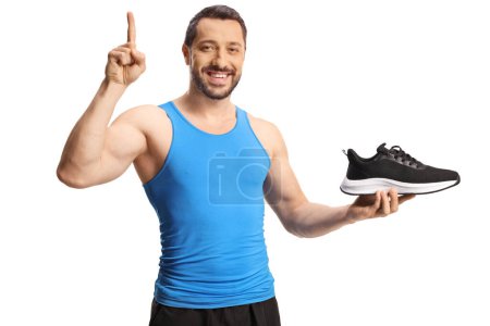 Téléchargez les photos : Fit homme tenant une chaussure et pointant vers le haut isolé sur fond blanc - en image libre de droit