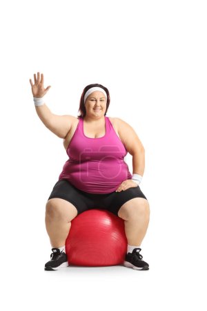 Photo for Corpulent woman sitting on an exercise ball and waving isolated on white background - Royalty Free Image