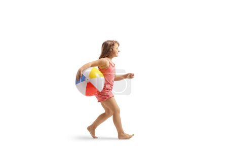Téléchargez les photos : Plan de profil complet d'une fille courant avec une balle de plage isolée sur fond blanc - en image libre de droit