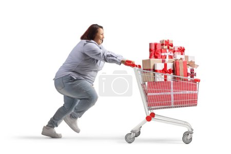Photo for Profile shot of a corpulent woman running with a presents in a shopping cart isolated on white background - Royalty Free Image