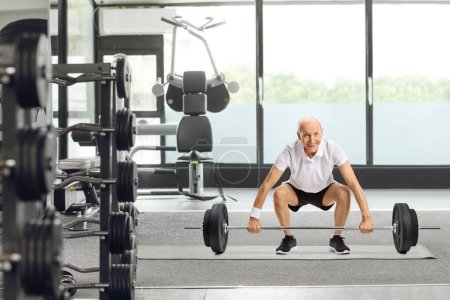 Photo for Senior man lifting a barbell at a gym - Royalty Free Image