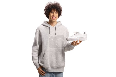 Photo for Guy holding a white sneaker and smiling isolated on white background - Royalty Free Image