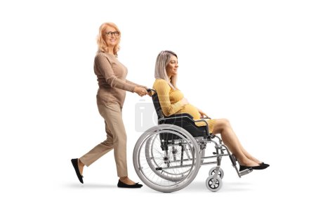 Photo for Middle aged woman pushing a pregnant woman in a wheelchair isolated on white background - Royalty Free Image