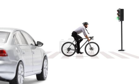 Photo for Profile shot of a businessman riding a bicycle with a helmet in fromt of a car at pedestrian crossing isolated on white background - Royalty Free Image