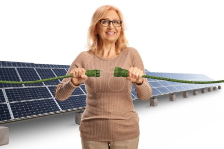 Téléchargez les photos : Femme mûre souriante à un champ solaire branchant des câbles électriques verts isolés sur fond blanc - en image libre de droit
