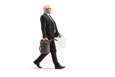 Téléchargez les photos : Photo de profil pleine longueur d'un homme d'affaires mature marchant et portant une cartouche de gaz isolée sur fond blanc - en image libre de droit