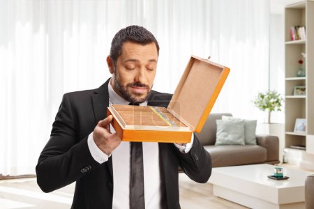 Foto de Hombre disfrutando del olor de una caja de cigarros en casa en una sala de estar - Imagen libre de derechos