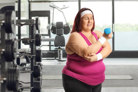 Photo for Plus size woman with an elbow sports injury at the gym - Royalty Free Image
