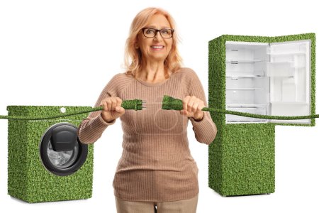 Foto de Mujer enchufando cables eléctricos verdes frente a electrodomésticos eficientes aislados sobre fondo blanco - Imagen libre de derechos