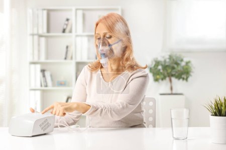 Photo for Woman turning on a nebulizer at  home, healthcare medical treatment concept - Royalty Free Image