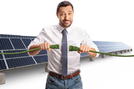 Photo for Businessman in front of solar panels holding green electric cables isolated on white background - Royalty Free Image
