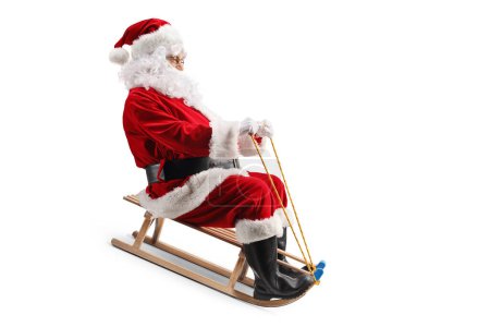 Téléchargez les photos : Père Noël chevauchant sur un traîneau en bois isolé sur fond blanc - en image libre de droit