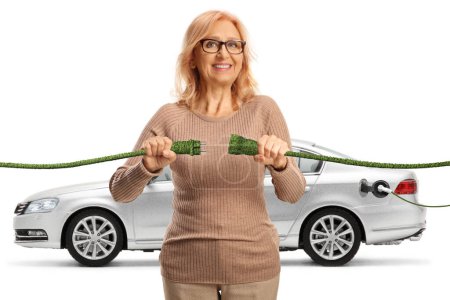 Photo for Happy mature woman plugging in green electric cables for an electric car isolated on white background - Royalty Free Image