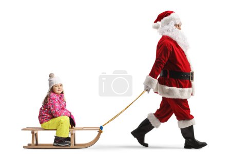 Téléchargez les photos : Santa clus tirant une petite fille sur un traîneau en bois isolé sur fond blanc - en image libre de droit