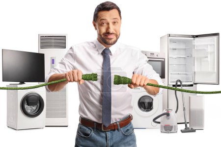 Foto de Hombre enchufando cables verdes frente a electrodomésticos de bajo consumo aislados sobre fondo blanco - Imagen libre de derechos