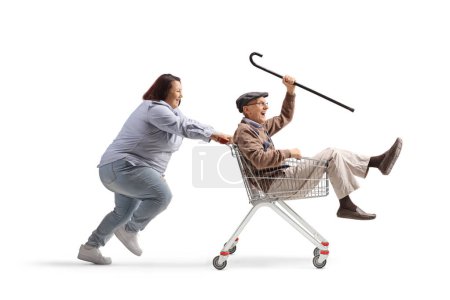 Téléchargez les photos : Femme poussant un retraité âgé heureux à l'intérieur d'un panier isolé sur fond blanc - en image libre de droit