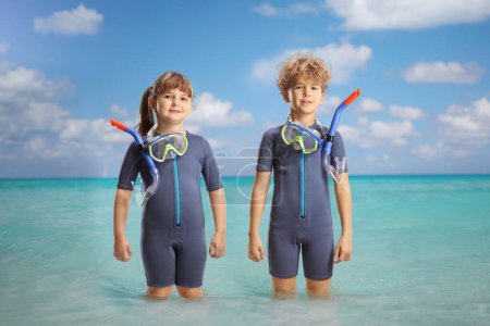 Foto de Chica y niño en trajes de neopreno y máscaras de buceo de pie en el mar - Imagen libre de derechos