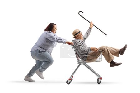Photo for Woman pushing an elderly gentleman inside a shopping cart isolated on white background - Royalty Free Image