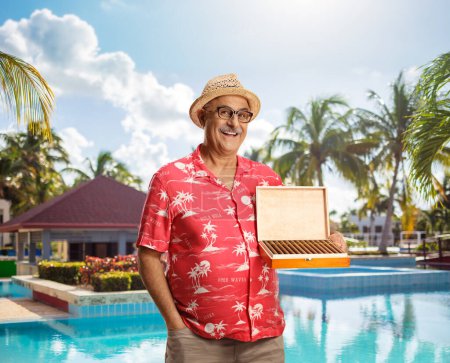 Foto de Turista maduro sosteniendo una caja de puros junto a una piscina en Cuba - Imagen libre de derechos
