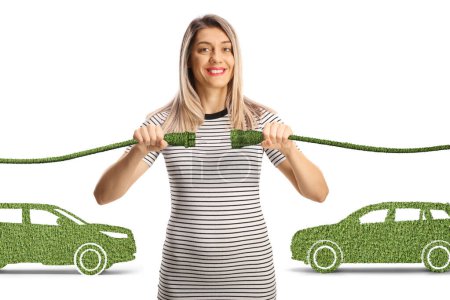 Foto de Mujer joven sosteniendo cables verdes frente a coches eléctricos aislados sobre fondo blanco - Imagen libre de derechos