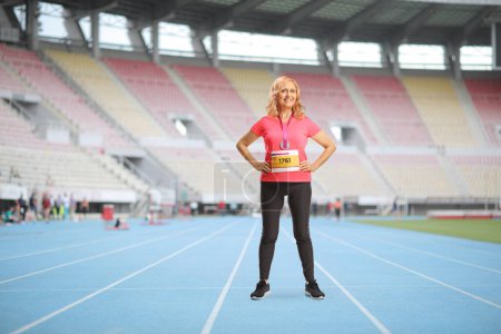 Foto de Retrato completo de una corredora madura parada en una pista de atletismo en un estadio - Imagen libre de derechos