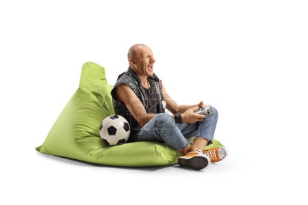 Foto de Hombre sentado en un sillón beanbag y jugando al fútbol videojuego con joystick aislado sobre fondo blanco - Imagen libre de derechos