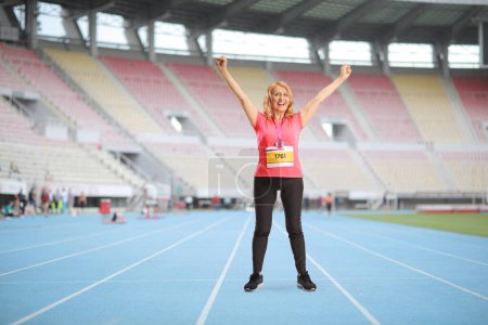 Foto de Retrato completo de una corredora madura celebrando la victoria en un estadio deportivo - Imagen libre de derechos