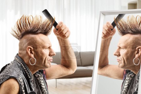 Man combing his mohawk hairstyle with a brush in front of a mirror at home