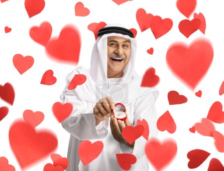 Téléchargez les photos : Homme arabe souriant tenant une bague de fiançailles dans une boîte sous les cœurs tombés - en image libre de droit