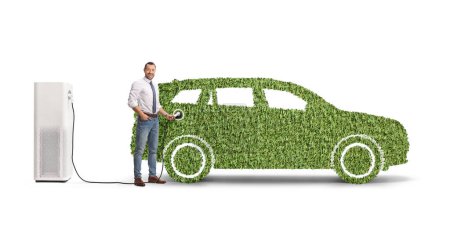 Téléchargez les photos : Homme d'affaires charge vert SUV électrique et regardant la caméra isolée sur fond blanc - en image libre de droit