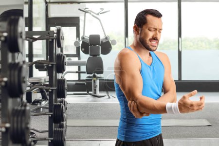Téléchargez les photos : Atlete masculin à une salle de gym se sentant douleur au coude, concept de blessure sportive - en image libre de droit