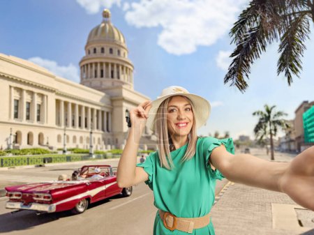Foto de Jovencita feliz con sombrero de paja tomando una selfie frente al edificio El Capitolio en La Habana, Cuba - Imagen libre de derechos