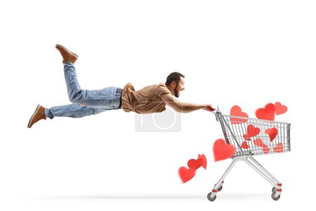 Foto de Hombre volando y sosteniendo un carro de compras con corazones rojos aislados sobre fondo blanco - Imagen libre de derechos