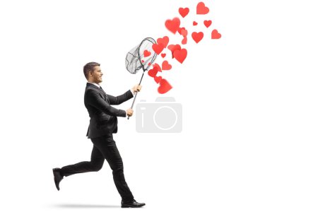 Téléchargez les photos : Homme en costume noir courant et attrapant les cœurs avec un filet isolé sur fond blanc - en image libre de droit
