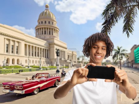 Photo for African american young man taking a photo with a smartphone in Havana, Cuba - Royalty Free Image