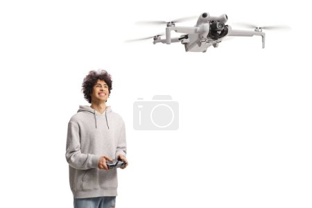 Téléchargez les photos : Joyeux jeune homme pilotant un drone avec un dispositif de contrôleur et regardant isolé sur fond blanc - en image libre de droit