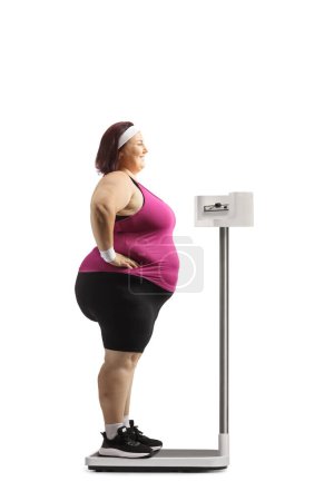 Photo for Young woman in sportswear standing on a medical weight scale isolated on white background - Royalty Free Image
