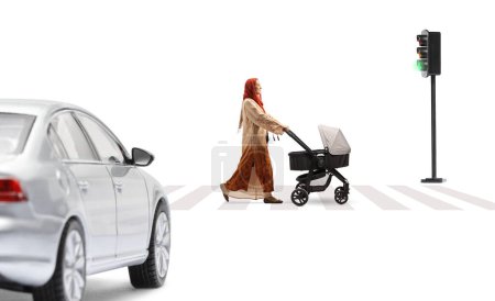 Photo for Full length profile shot of a mother in a hijab pushing a baby stroller at a pedestrian crossing isolated on white background - Royalty Free Image