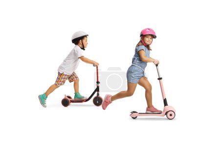 Téléchargez les photos : Enfants sur scooters push isolés sur un fond blanc - en image libre de droit