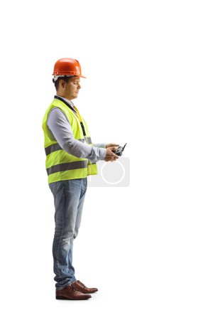 Photo for Engineer in a safety vest looking at a drone remote controller isolated on white background - Royalty Free Image