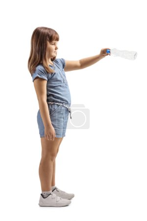 Téléchargez les photos : Photo de profil pleine longueur d'une petite fille jetant une bouteille en plastique isolée sur fond blanc - en image libre de droit