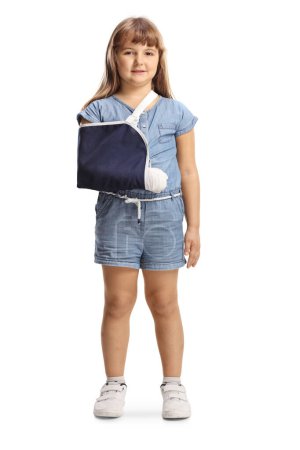 Téléchargez les photos : Portrait complet d'un enfant avec un bras cassé portant une fronde isolée sur fond blanc - en image libre de droit