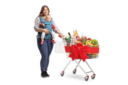 Foto de Madre con un bebé en un portador y un carrito de compras atado con una cinta roja aislada sobre fondo blanco - Imagen libre de derechos