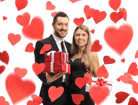 Téléchargez les photos : Jeune couple tenant des cadeaux sous une pluie de cœurs isolés sur fond blanc - en image libre de droit