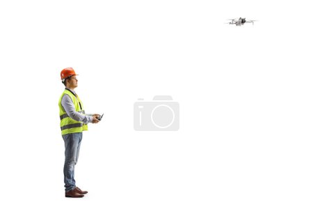 Photo for Engineer in a safety vest flying a drone with a remote controller isolated on white background - Royalty Free Image