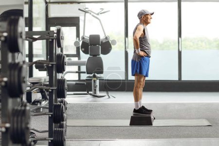 Photo for Full length profile shot of an elderly man at a gym stading on a step aerobic platform - Royalty Free Image