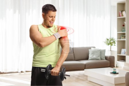 Photo for Man with an inflamed shoulder lifting weights in an apartment - Royalty Free Image